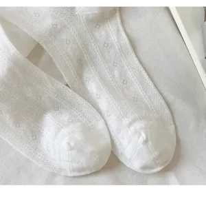 Gros plan de chaussettes en tricot blanc avec motif en maille losange et texture douce.