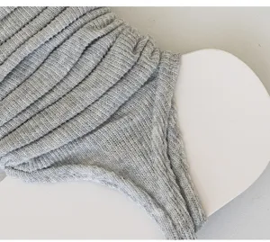 Detailed view of grey knitted stirrup socks, soft ribbed leg warmers for women spring autumn.