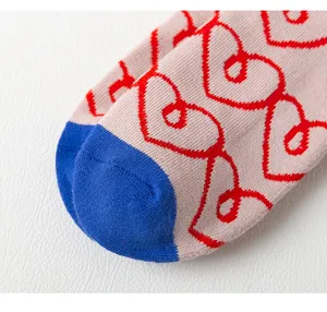 Close-up detail van dikke badstof damessokken met rood hartjespatroon en blauwe teen.
