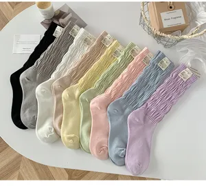 Chaussettes empilées colorées avec des étiquettes en tissu sur une table blanche.