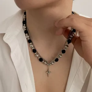 Gros plan sur le collier streetwear à perles noires et argentées avec pendentif.