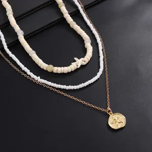 Detailed shot of multi-layer starfish pendant necklace with wooden beads and gold chain style.