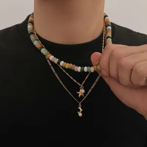 Collana multistrato con perle colorate e ciondoli dorati a stella marina e luna.