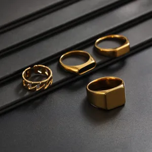 Close-up detail of golden stainless steel ring set, featuring smooth geometric signet and chain links.