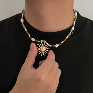 Primo piano dettagliato della collana di perle e conchiglie con ciondolo sole in metallo.