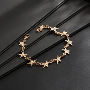 Gedetailleerd close-up van goudkleurige sterren armband met schitterende strass op zwart display.