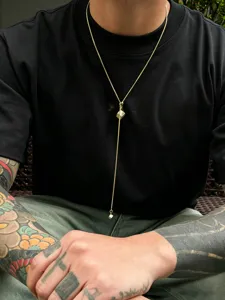 Detailed close-up view showcasing the stylish gold metal cube Y-necklace worn on black t-shirt.