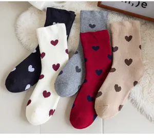 Gros plan de chaussettes mi-tubes en coton épais pour femmes avec motif de cœur tricoté mignon.