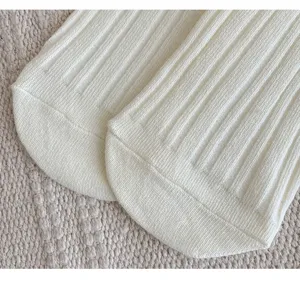 Detailopname van witte geribbelde katoenen damessokken met fijne gebreide textuur.