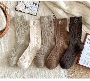 Detailed view of warm cable knit wool socks featuring cute heart embroidery and ribbed cuffs.