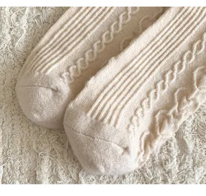 Detailed close-up of cozy women's thick warm cable knit wool socks in beige texture design.