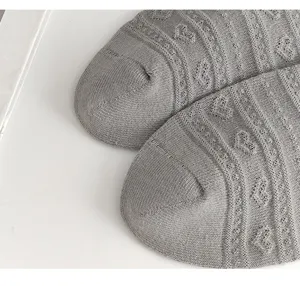 Detailaufnahme grauer Damenstrümpfe mit retro Herzmuster und weichem Strickmaterial.