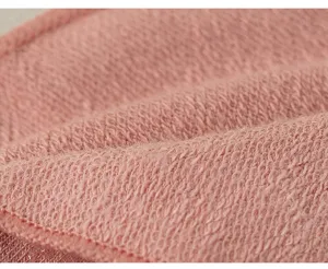 Detailed shot of soft pink knit fabric texture, showing smooth loop weave material closely.