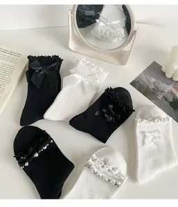 Detail view of Japanese Lolita style socks with delicate ruffles, bows and pearl decorations.