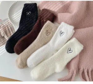 Close-up of thick fuzzy winter socks with cute heart embroidery, soft plush texture details.
