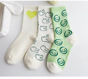 Primo piano dettagliato di calzini carini con cuore verde, coccodrillo e motivi smiley.