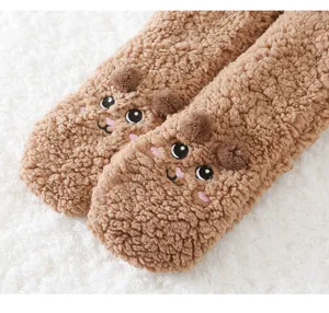 Nahaufnahme der weichen braunen Fleece-Wohnsocken mit süßem besticktem Tiergesicht Detail.