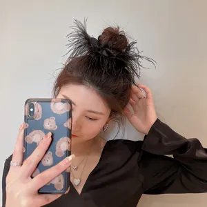 Close-up of black ostrich feather hair scrunchie, showcasing fluffy texture and elegant design detail.