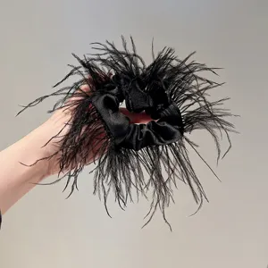 Detailed view of the elegant black feather scrunchie, showcasing fluffy texture and satin.
