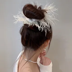 Detail view of fluffy white feather hair scrunchie bun holder accessory for elegant daily style.