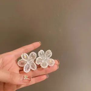 Close-up detail of crystal flower earrings featuring transparent petals and beaded trim.