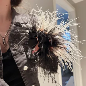 Close-up detail showing the fluffy texture of the black and white ostrich feather hair scrunchie.