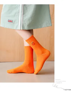 Gros plan détaillé de chaussettes orange vif avec un joli motif de broderie de fruits.