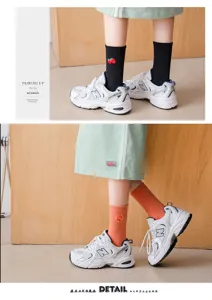 Vue détaillée de chaussettes mi-hautes brodées de fruits mignons, motifs fraise et orange.