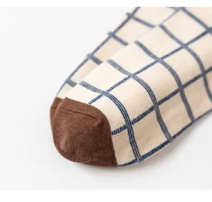 Gros plan détail de chaussettes en coton pour femmes avec motif à carreaux et bout marron.