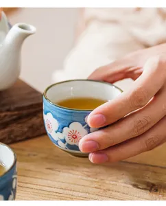 Close-up of hand-painted blue and white ceramic teacup with plum blossom pattern detail.