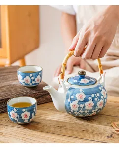 Detail shot of hand-painted ceramic teapot with bamboo handle and floral pattern in use.