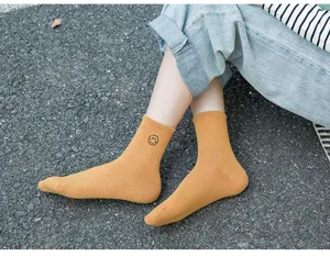 Nahaufnahme von gelben Baumwollsocken mit niedlichem gesticktem Smiley Motiv im Detail.