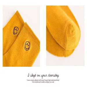 Detailansicht gelber Baumwollsocken mit süßen bestickten Smiley-Gesichtern und weicher Strick.