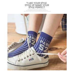 Nahaufnahme gestreifter Baumwollsocken mit Nummernprint, Alltagsszene beim Schuhebinden.