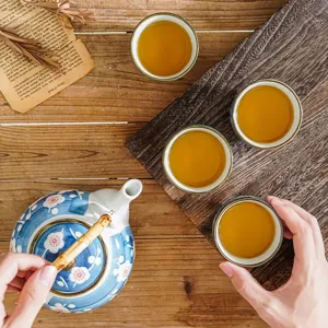 Hand-painted ceramic tea set with one teapot and four cups in top-down view arrangement.
