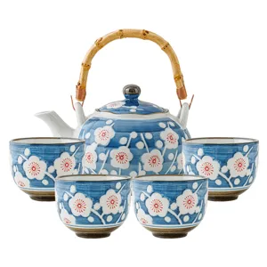 Japanese ceramic tea set with teapot and four cups, blue plum blossom design and bamboo handle.