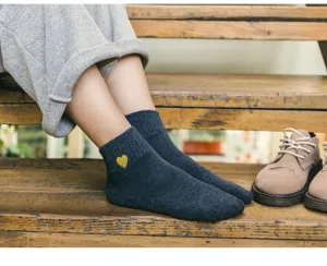 Gros plan de détail des chaussettes en coton côtelé gris foncé avec broderie cœur dorée.