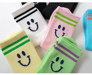 Nahaufnahme von süßen Baumwollsocken mit Doppelstreifen und gestricktem Smiley-Gesicht.