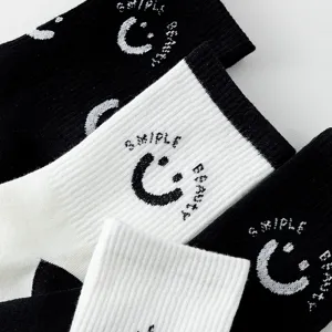 Calzini in cotone nero e bianco con motivo lavorato a maglia di viso sorridente e lettere chic.