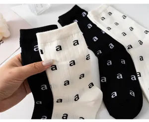 Détail en gros plan de chaussettes en coton noir et blanc avec motif de lettres partout.
