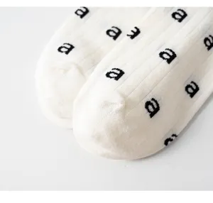 Gros plan de chaussettes pour femmes en tricot avec motif de lettres noires chic.