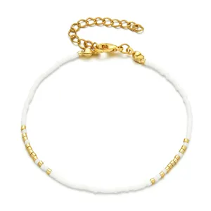 Détail de bracelet de perles délicat montrant des perles blanches, tubes dorés et fermoir.