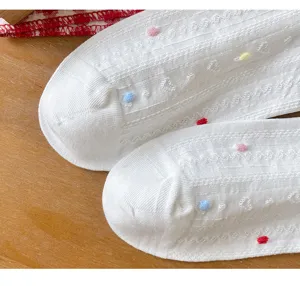 Calcetines cortos blancos de mujer con pompones coloridos y relieve delicado. Ideales para el verano.