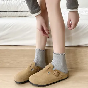 Cómodos zuecos de ante marrón combinados con calcetines grises con volantes para mujer.