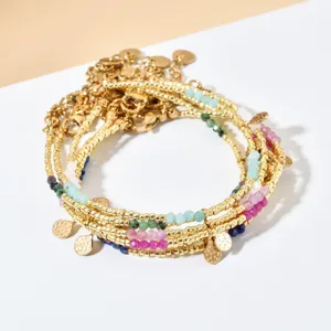 Close-up detail van de meerstrengige kralenarmband met kleurrijke edelstenen en gouden bedels.