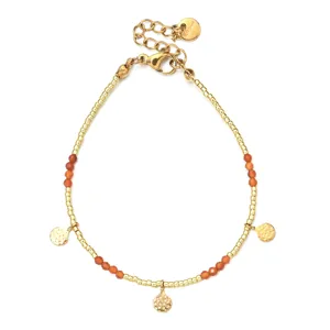 Gouden roestvrijstalen kralenarmband met rode edelstenen en gehamerde muntbedels detail.