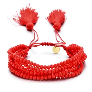 Pulsera multicapa de cuentas de cristal rojas con borlas colgantes y cordón ajustable.