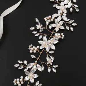 Detailed shot of handmade pearl bridal hair vine with gold leaves and crystals for wedding.