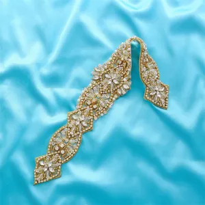 Vue détaillée d'une applique de ceinture de mariée en strass scintillants sur satin bleu.