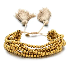 Vista de primer plano detallada de una pulsera de cuentas doradas facetadas con borlas.